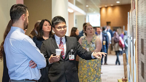 Residents discuss a research poster at the conference