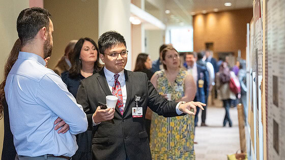 Residents discuss a research poster at the conference