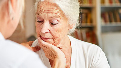 Older woman looking down with her chin resting on her hand