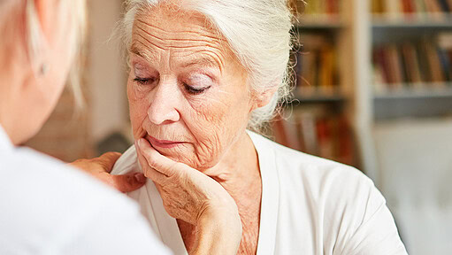 Older woman looking down with her chin resting on her hand