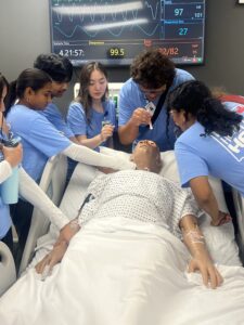 High school students collect around a manikin during a MASH camp at UAMS Northwest Regional Campus