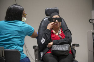 Mandy Ritok covers her left eye with a blinder and reads using her right eye during an exam