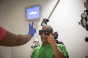 Anton Leviticus holds a blinder over his right eye and reads instructions from a UAMS staff member with his left eye