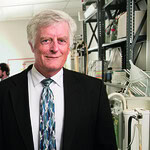Lawrence Cornett, Ph.D., director of the Arkansas INBRE program, standing in a lab wearing a suit and tie.