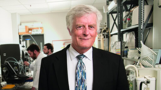 Lawrence Cornett, Ph.D., director of the Arkansas INBRE program, standing in a lab wearing a suit and tie.
