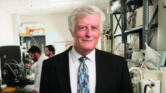 Lawrence Cornett, Ph.D., director of the Arkansas INBRE program, standing in a lab wearing a suit and tie.