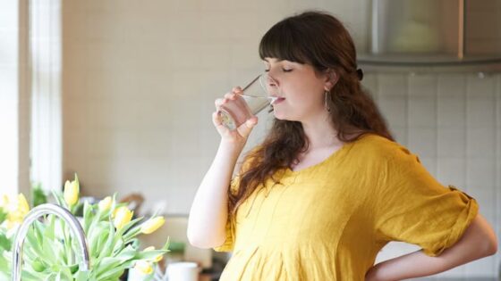 Pregnant women drinking a glass of water at the kitchen sink