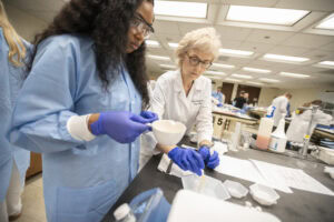 Melanie Reinhardt assists a student during compounding labs at summer pharmacy camp