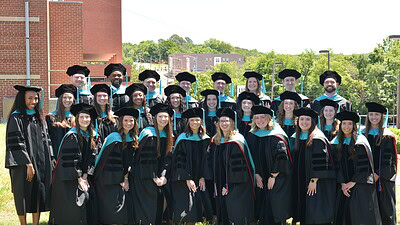 The UAMS Doctor of Physical Therapy class of 2026 poses in their regalia on the UAMS Northwest Campus lawn.