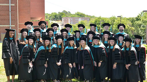 The UAMS Doctor of Physical Therapy class of 2026 poses in their regalia on the UAMS Northwest Campus lawn.