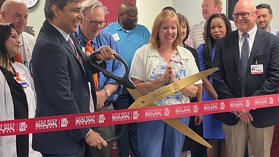 Rohit Dhall, M.D., chair of the UAMS Department of Neurology, prepares to cut the ribbon officially opening the UAMS Health Neurology Clinic in the Doctors Building for multiple sclerosis and headache patients as Michelle Krause, M.D., senior vice chancellor of UAMS Health, and Robert D. Robinson, M.D., dean of the UAMS College of Medicine and executive vice chancellor of UAMS, look on from the front row.