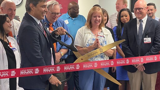 Rohit Dhall, M.D., chair of the UAMS Department of Neurology, prepares to cut the ribbon officially opening the UAMS Health Neurology Clinic in the Doctors Building for multiple sclerosis and headache patients as Michelle Krause, M.D., senior vice chancellor of UAMS Health, and Robert D. Robinson, M.D., dean of the UAMS College of Medicine and executive vice chancellor of UAMS, look on from the front row.