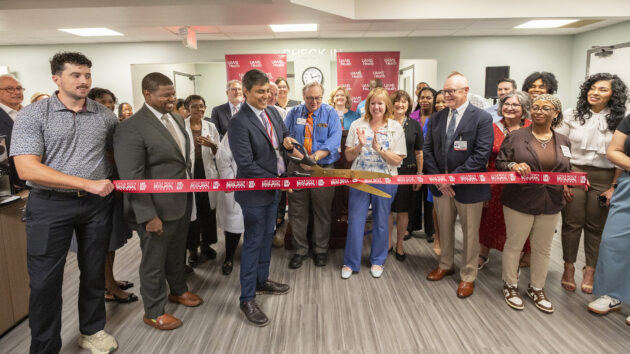 Rohit Dhall, M.D., prepares to cut the ribbon officially opening the UAMS Health Neurology Clinic in the Doctors Building as Jonathan Goree, M.D., (left of Dhall, front row), and Scott Lucchese (right of Dhall, front row), Michelle Krause, M.D., and Ron Robertson, M.D., look on.