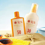 Photo of sunscreen bottles and sunglasses sitting on a blanket at the beach
