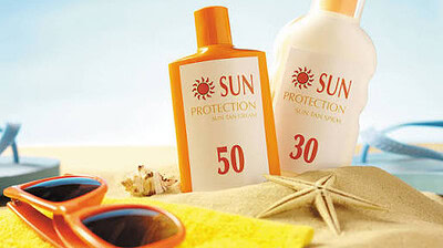 Photo of sunscreen bottles and sunglasses sitting on a blanket at the beach