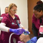 Four students from Southeast Arkansas College work to resuscitate a high-fidelity manikin during their July 9 visit to the UAMS College of Nursing’s Innovative Practice and Simulation Center.