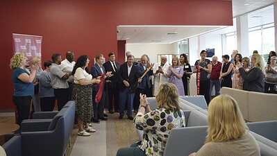 UAMS Chancellor C. Lowry Barnes, M.D., (center) smiles as onlookers clap after he cuts the ribbon to formally open the newest and largest UAMS Health Orthopaedic & Sports Medicine Clinic.