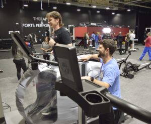 UAMS Health physical therapist Nicholas Hargett (left) and athletic trainer Landon Simpson demonstrate how to use the Boost Microgravity Treadmill, which allows the user to run or walk anywhere from 100% to as low as 20% of their bodyweight.