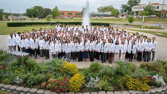 Group photo in front of UAMS fountain of UAMS College of Medicine Class of 2026 in white coats