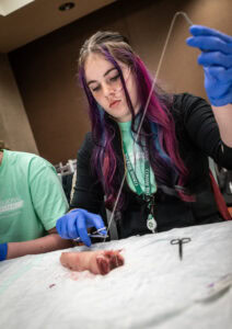 Quin Farmer, a senior from Bauxite, sutures a pig foot at the MASH Camp at Conway Regional.