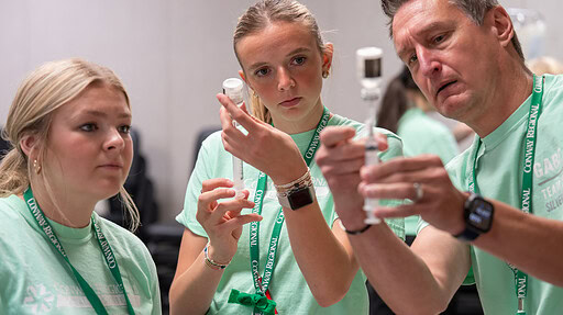 Two MASH students learn how to draw medicine from a vial from an instructor.