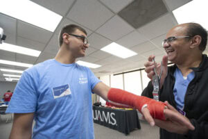 Christopher Phillips from Pine Bluff High School laughs with John Makary, M.D., as he pries open his cast.