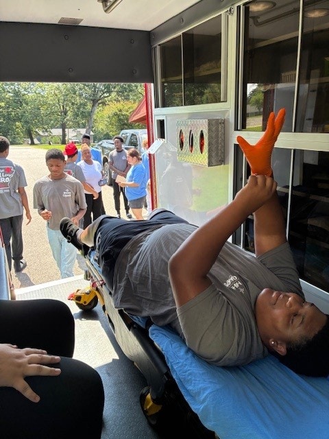A boy puts on a glove inside an ambulance at the Mini MASH Camp in Monticello.