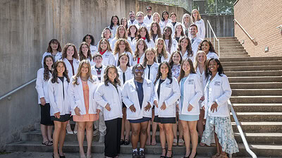 Students and faculty of the Department of Audiology and Speech Pathology gather on the steps outside the I. Dodd Wilson Building after the white coat ceremony for the Doctor of Audiology Class of 2030 and the Master of Science in Speech-Language Pathology Class of 2028.