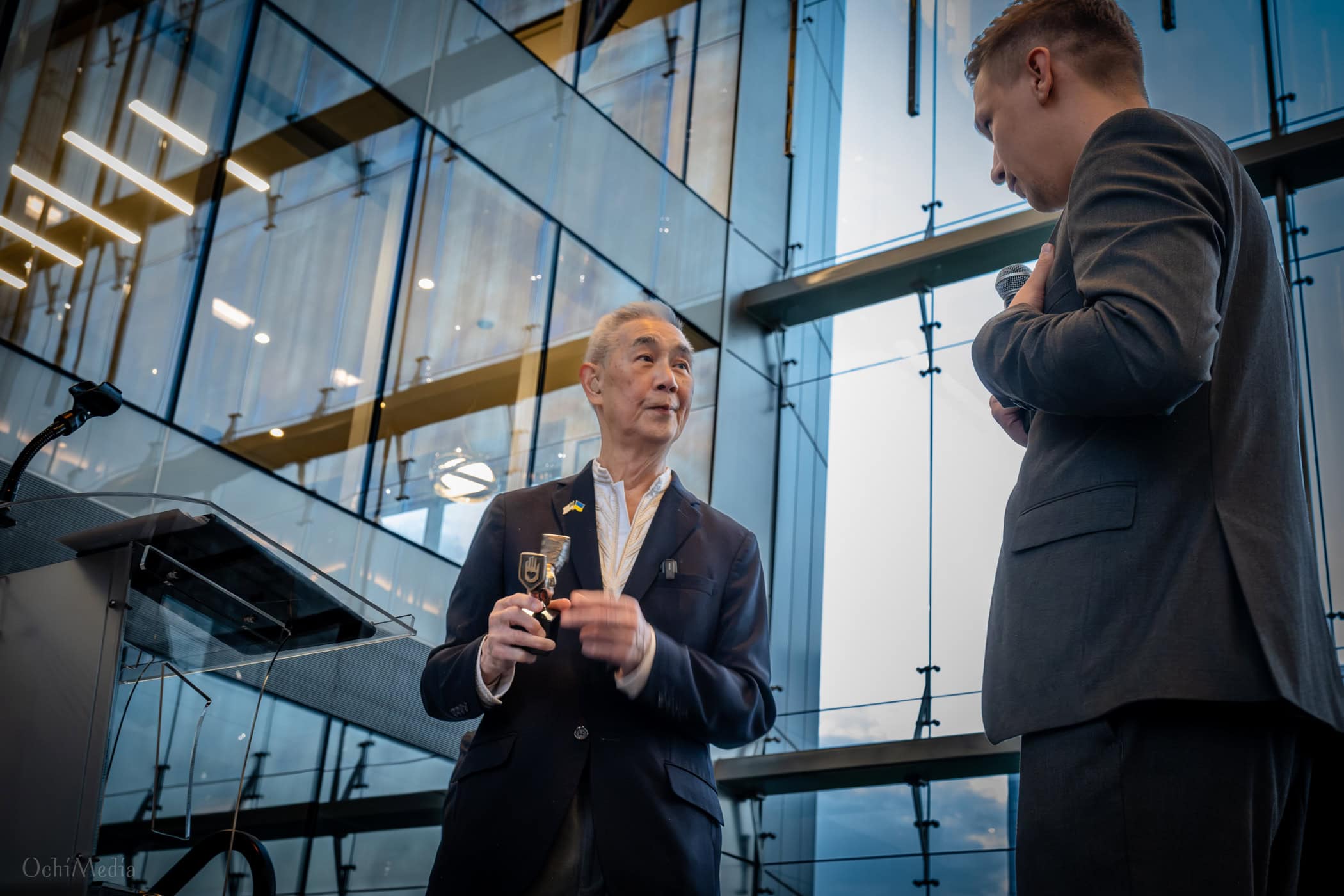 Suen holds a custom Ukrainian commemorative award presented by Ed’s Friends Ukraine. The front features the Tryzub (the Coat of Arms / Trident of Ukraine), placed on an emblem plate. The trophy was fashioned from a spent artillery shell casing or military war-metal relic.