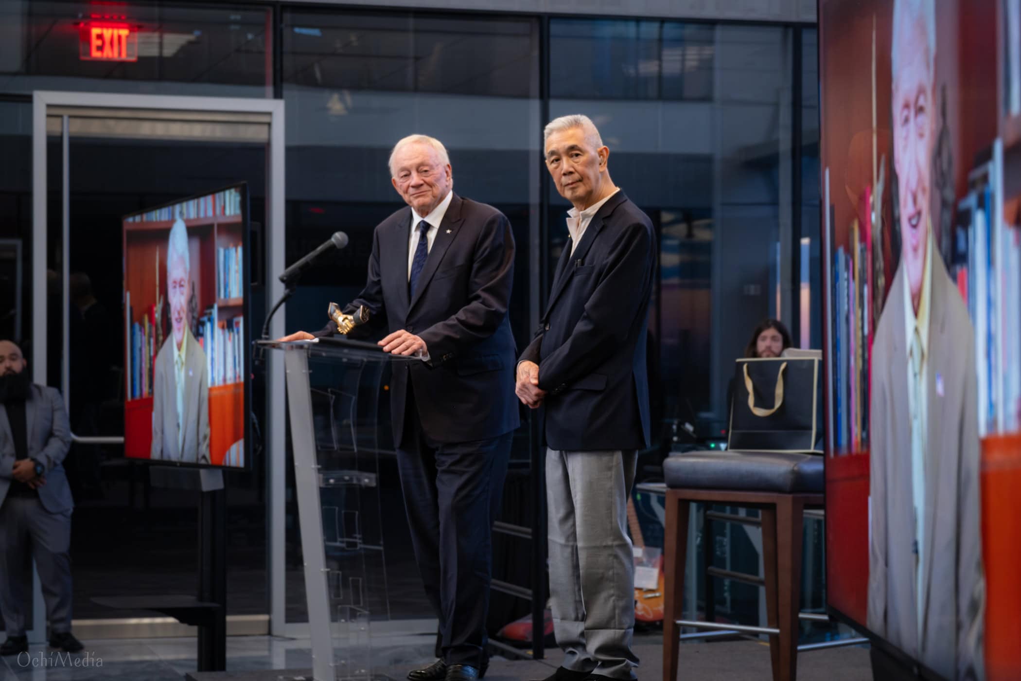 Suen, right, and Jerry Jones, owner of the Dallas Cowboys NFL football team, stop on stage to watch and listen to a testimonial video from President Bill Clinton.