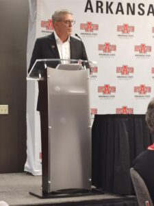 Tim Langford, M.D., stands behind a podium in front of an A-State background to accept the award.