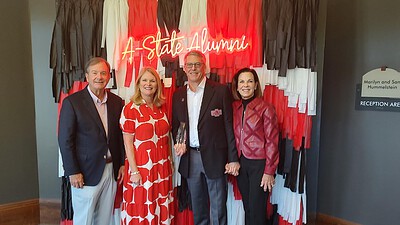 Tim Langford, M.D., and his wife, Terri, with UAMS Chancellor C. Lowry Barnes, M.D., and his wife, Tanya, pose together in front of an A State backdrop after the ceremony.