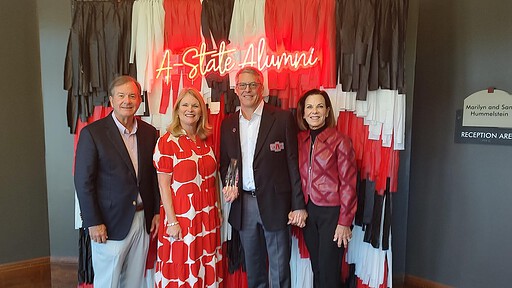 Tim Langford, M.D., and his wife, Terri, with UAMS Chancellor C. Lowry Barnes, M.D., and his wife, Tanya, pose together in front of an A State backdrop after the ceremony.