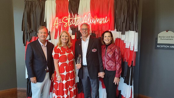 Tim Langford, M.D., and his wife, Terri, with UAMS Chancellor C. Lowry Barnes, M.D., and his wife, Tanya, pose together in front of an A State backdrop after the ceremony.