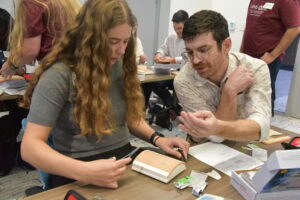 Resident shows medical student how to suture.