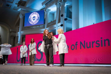 A student dons her white coat during the College of Nursing ceremony.